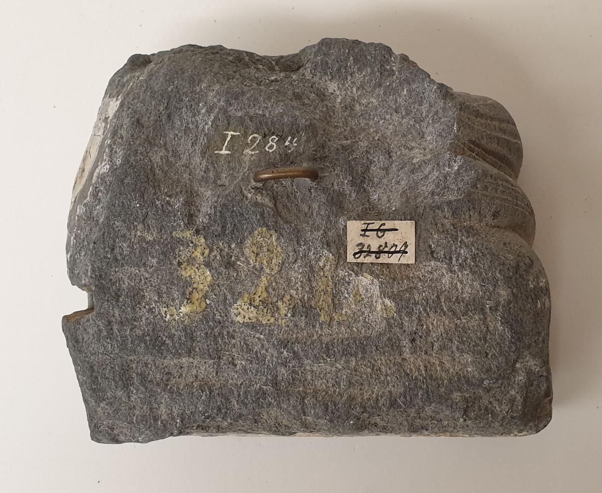 Unterkörper eines meditierenden Buddha auf Löwenthron mit Vorhangmotiv (Fragment). Sockelrelief: Knieender Adorant vor Feuerständer (Fragment)