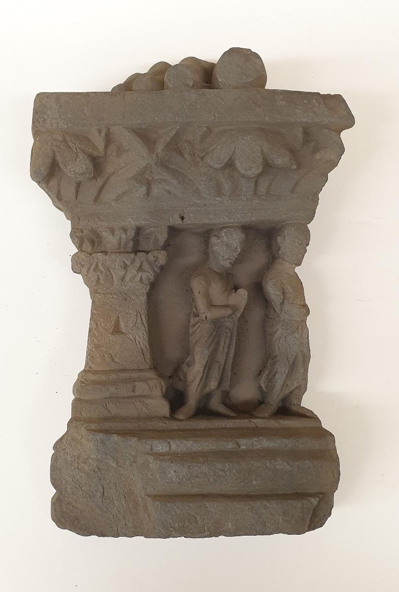 Fuß eines stehenden Buddha (Fragment). Sockelrelief: zwei Mönche unter Akanthusblattfries