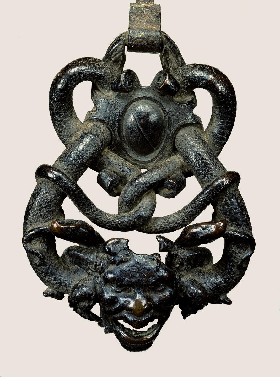 Schlangen um Maske und Wappen