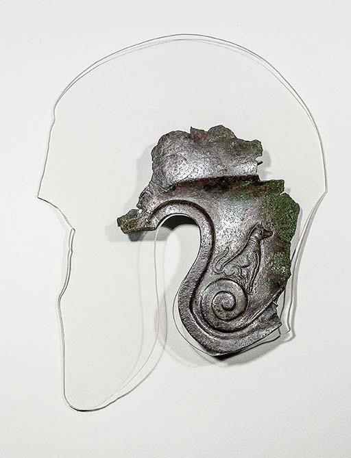 Fragment eines Helms mit sitzendem Hund