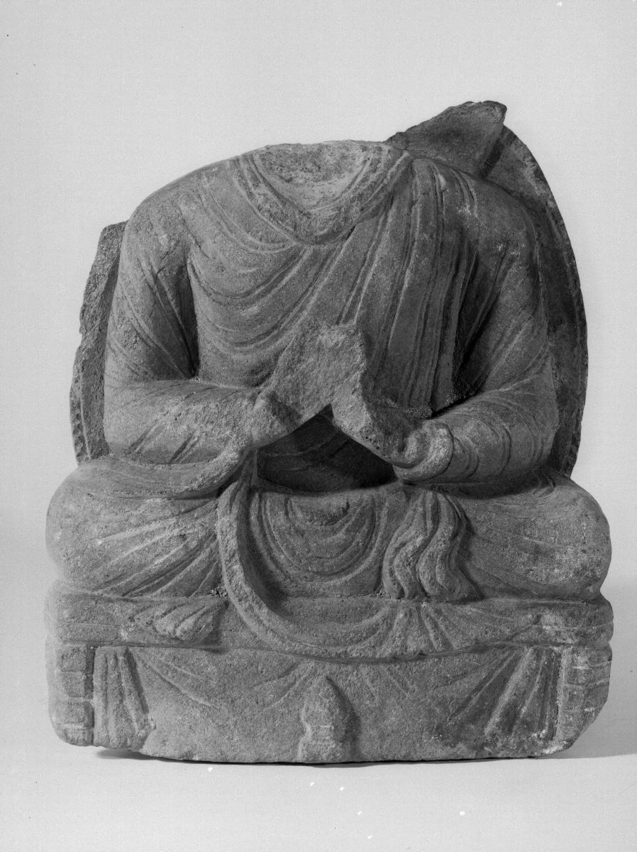 Torso eines sitzenden Buddha in Lehrgeste (dharmachakra-mudra) auf Thron mit Vorhangmotiv (Fragment). Sockelrelief: Feuerständer