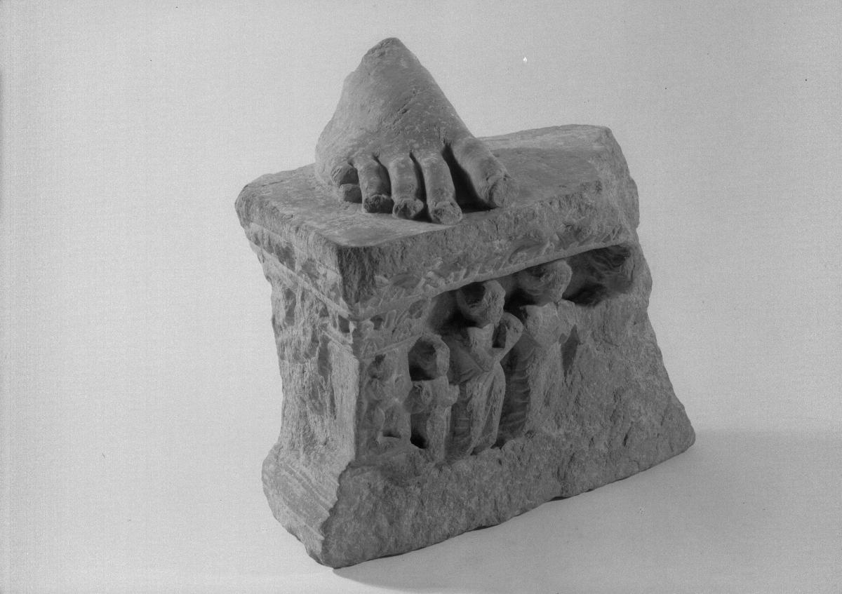 Fuß eines stehenden Buddha (Fragment).
Sockelrelief: Verehrungsszene