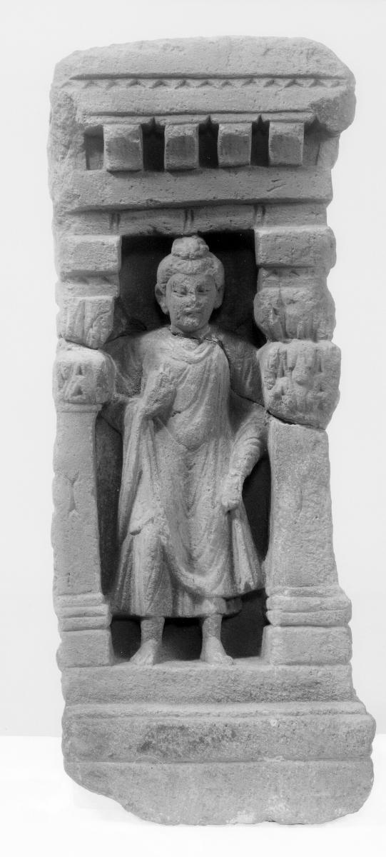 Stehender Buddha in Schutzgeste (abhaya-mudra) zwischen zwei Säulen unter Kragsteinfries (Fragment)