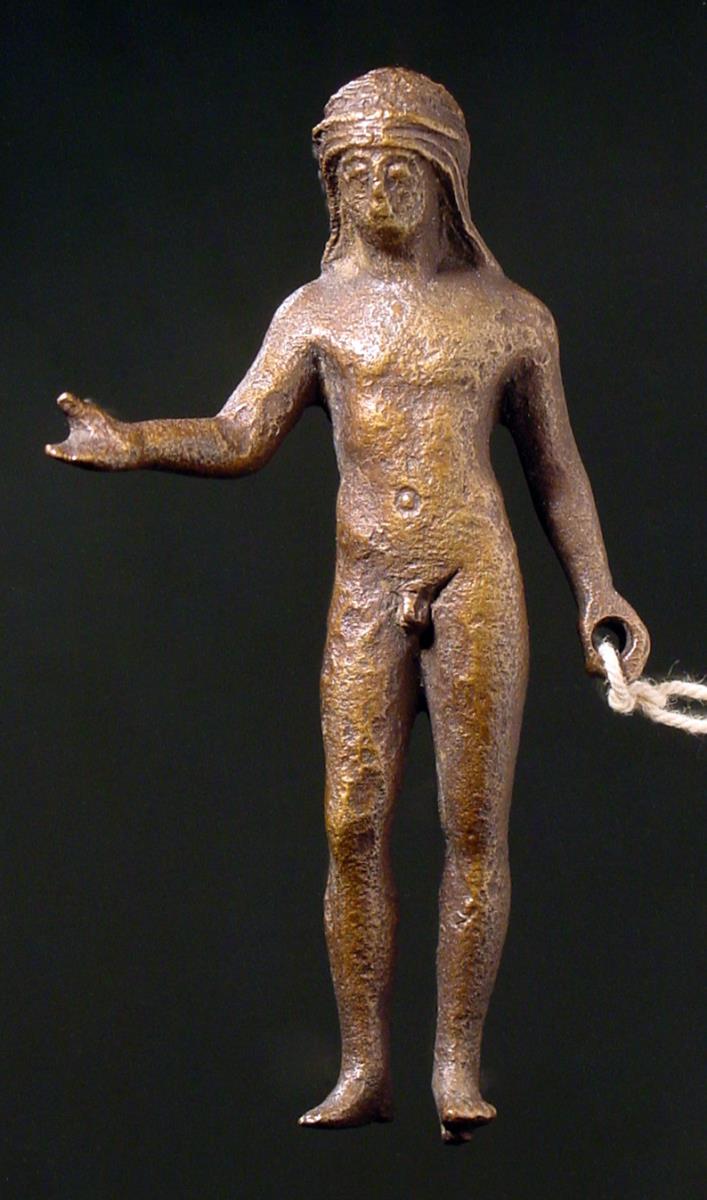 Statuette eines Jünglings mit langem Haar, die Rechte vorstreckend, in der linken Hand ein rundes Loch für einen Gegenstand, unter dem linken Fuß ein Zapfen