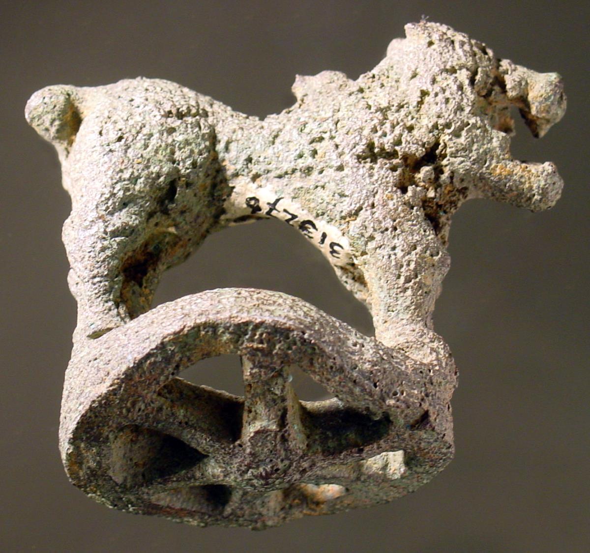 Stark korrodierte geometrische Statuette eines Löwen auf verbogener radförmiger Basis