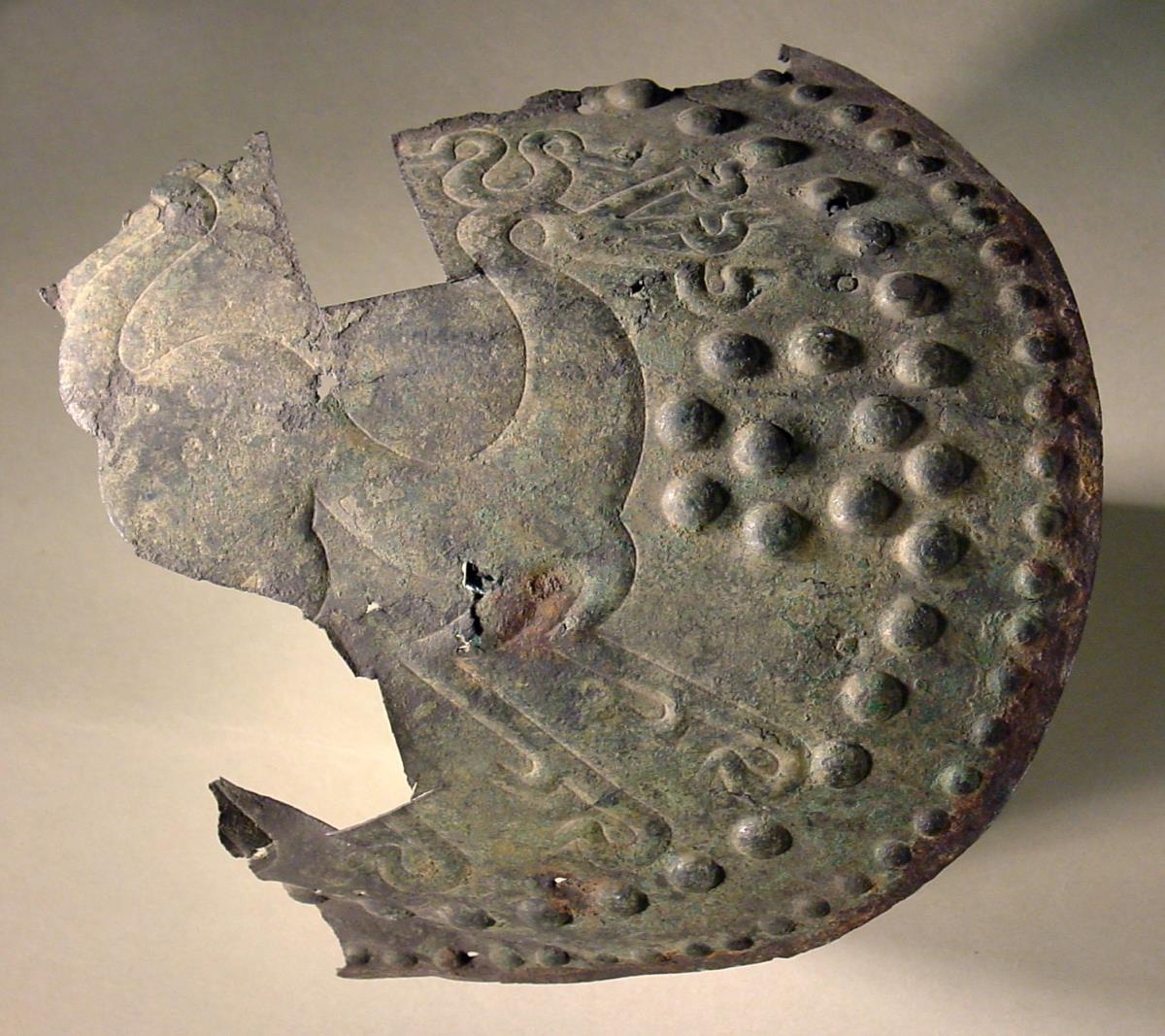Fragment eines Oberschenkelschutzes von Blech mit Buckeln und Ornament