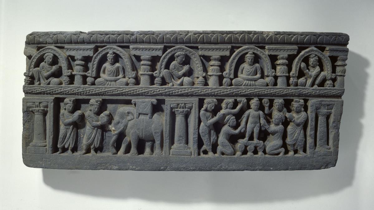 Mehrreihiger Fries mit erzählenden Szenen: erstes Bad des neu geborenen Siddhartha Gautama (unten rechts) sowie Heimkehr nach Lumbini (unten links); darüber Schmuckfries mit meditierenden Buddhas und Adoranten unter Chaitya-Bögen