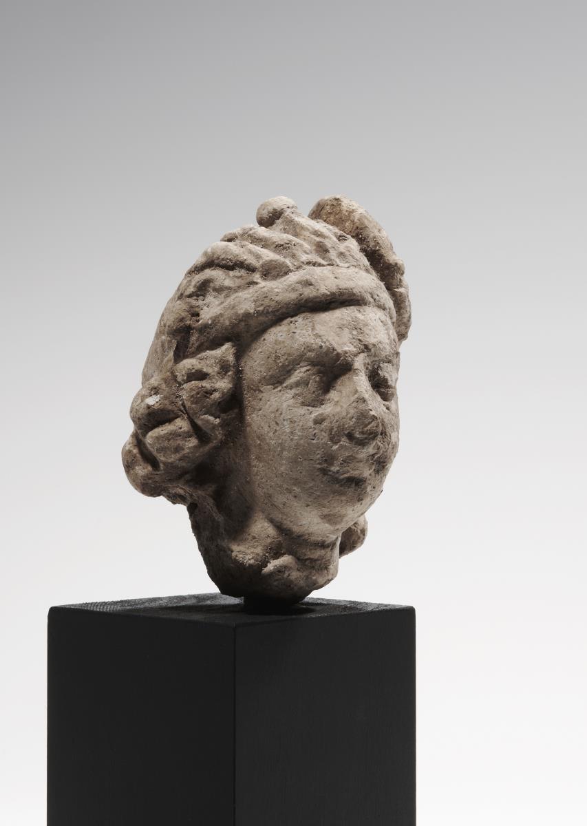 Kopf eines Mannes mit Stirnreif und großer seitlicher Schmuckrosette