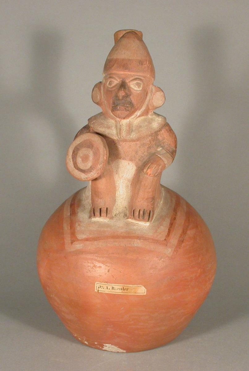 Applikation: sitzende anthropomorphe Figur mit Schild