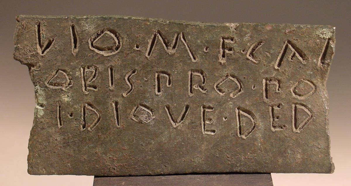 Bruchstück eines Bronzestreifens mit dreizeiliger Inschrift aus altlateinischen Buchstaben