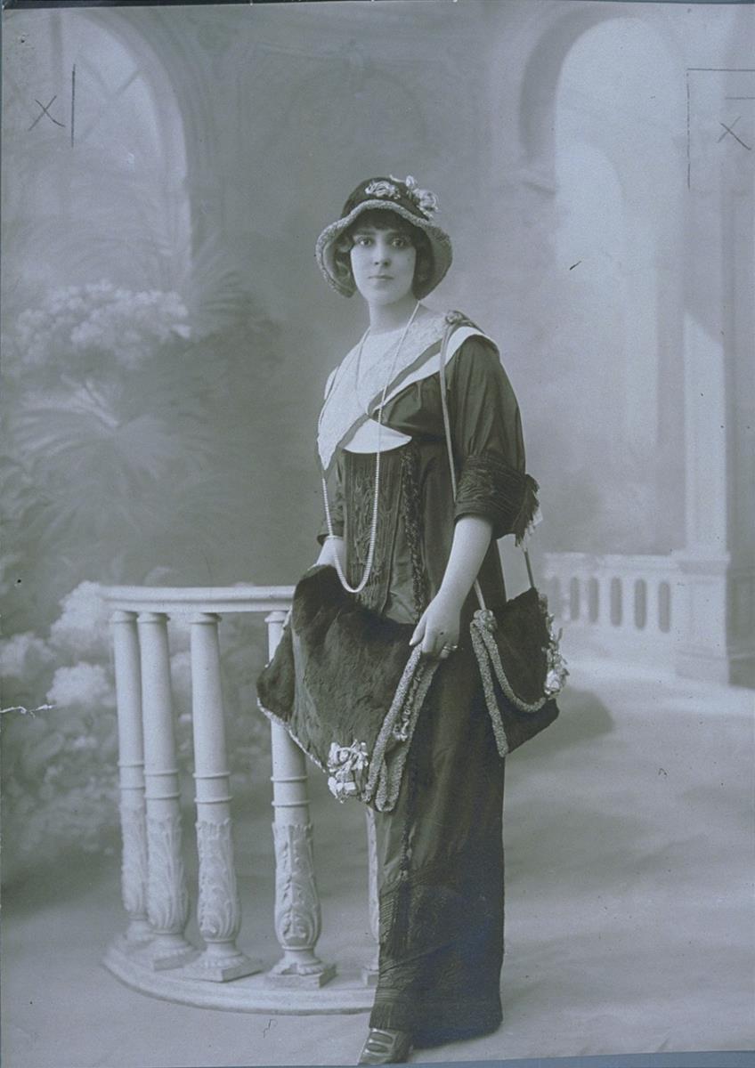Frau in Kleid mit Muff, Tasche und Hut von Lewis