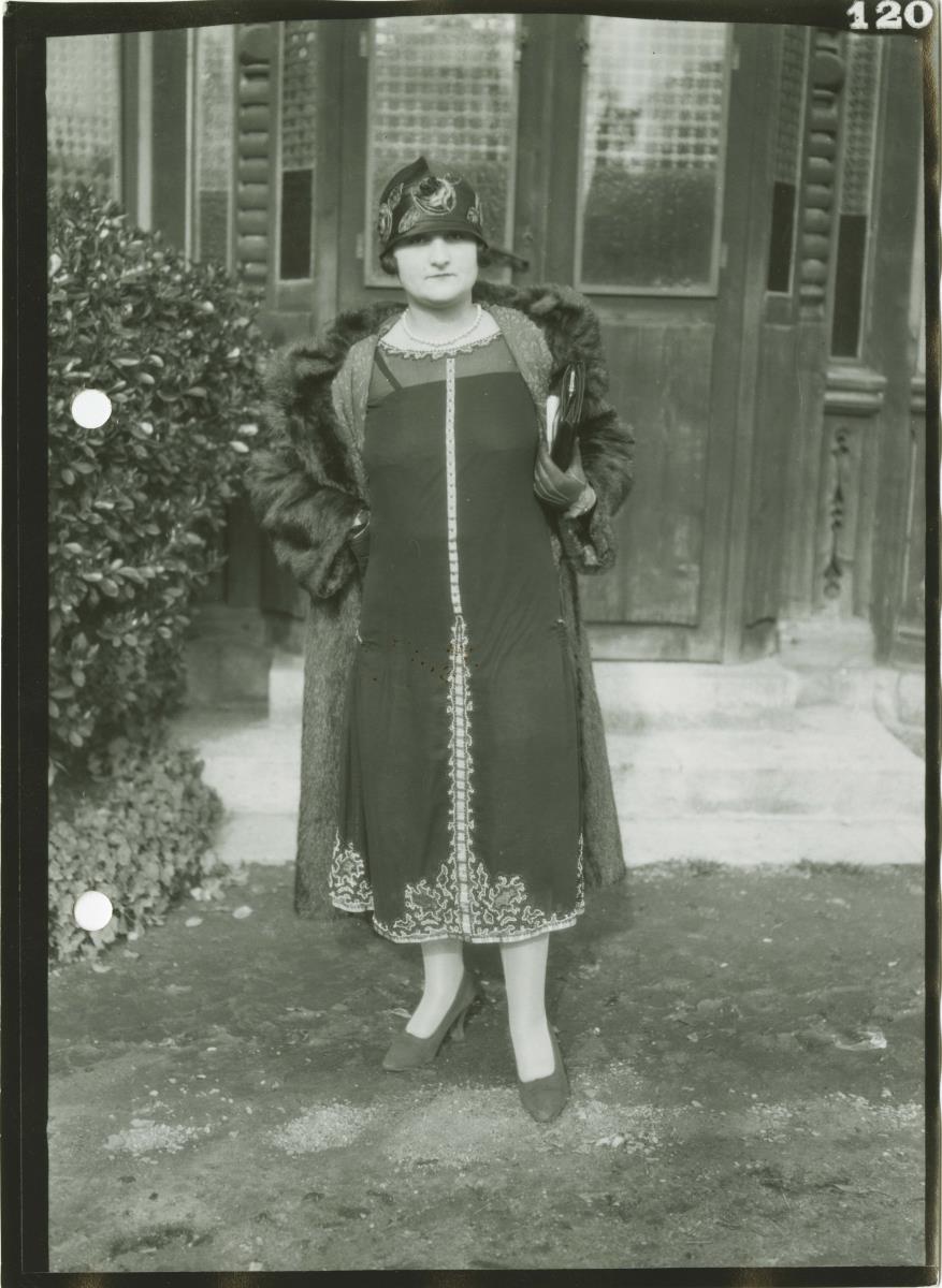Frau in Kleid und Mantel auf dem Rennplatz