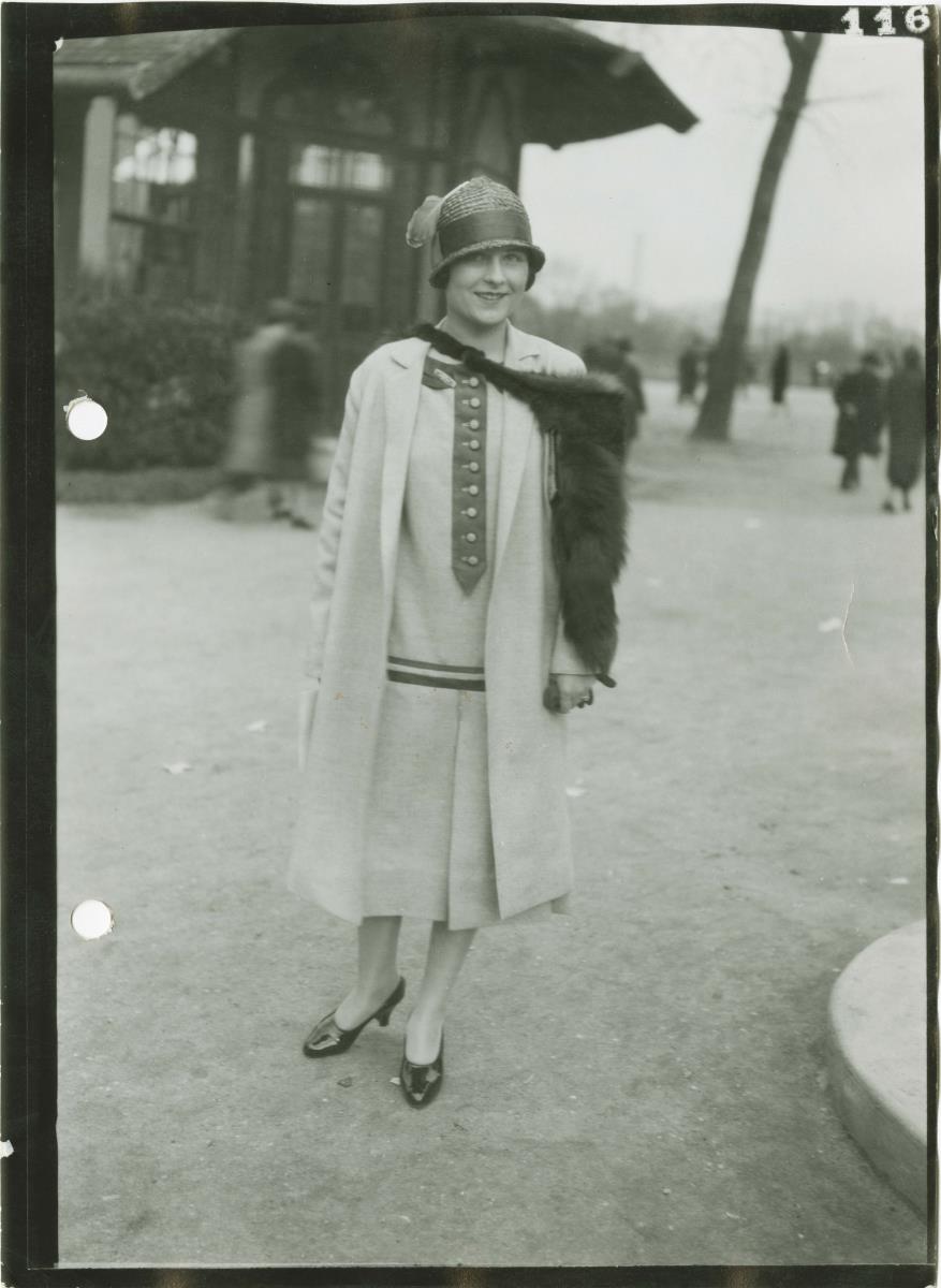 Frau in Kleid und Mantel auf dem Rennplatz