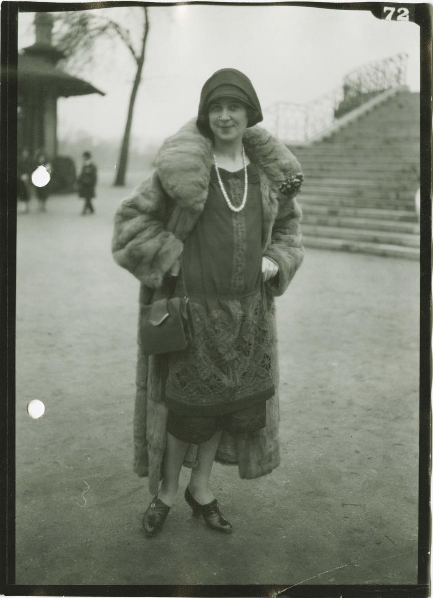 Frau in Kleid und Mantel auf dem Rennplatz