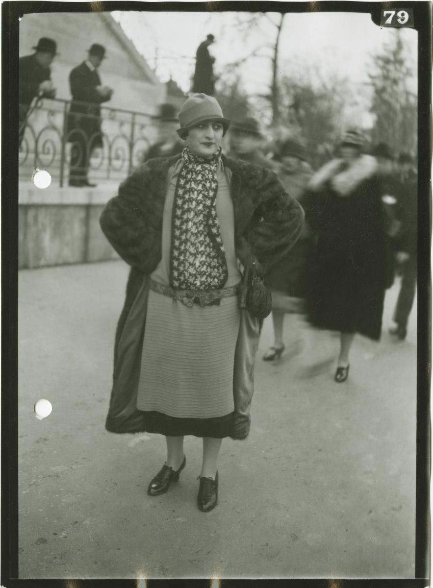 Frau in Kleid und Mantel auf dem Rennplatz
