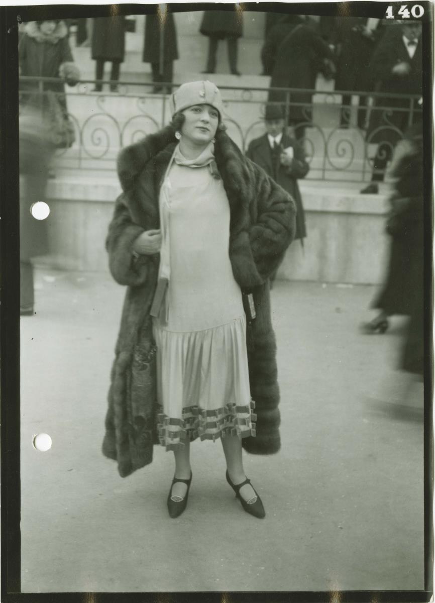 Frau in Kleid und Mantel auf dem Rennplatz