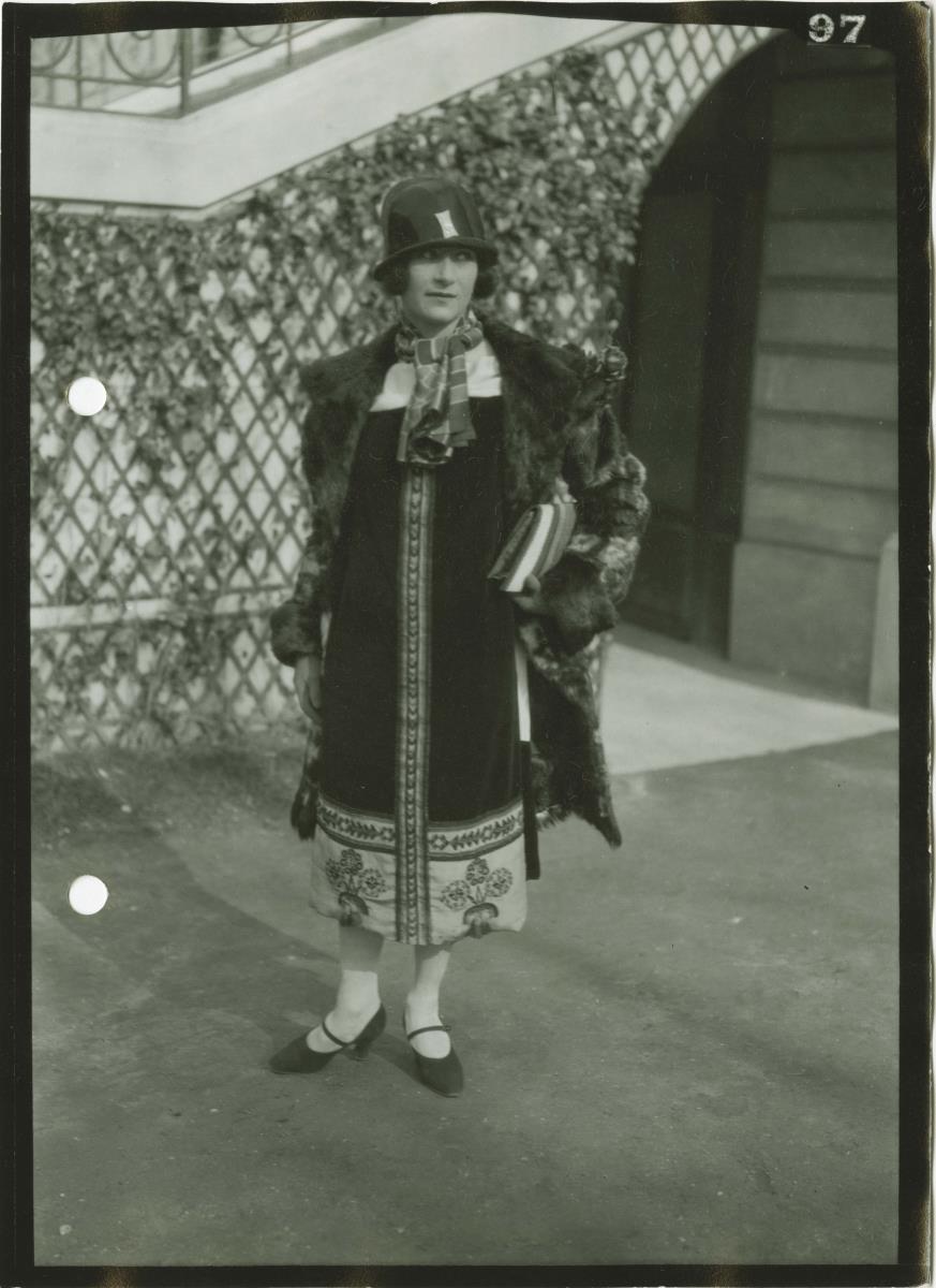 Frau in Kleid und Mantel auf dem Rennplatz