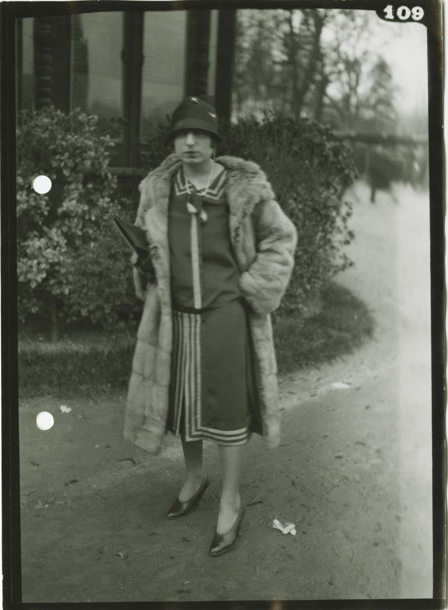 Frau in Kleid und Mantel auf dem Rennplatz