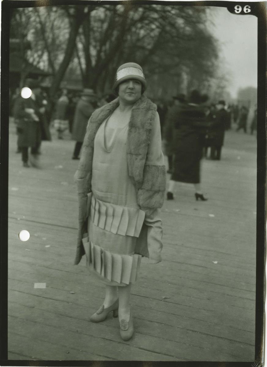 Frau in Kleid und Mantel auf dem Rennplatz