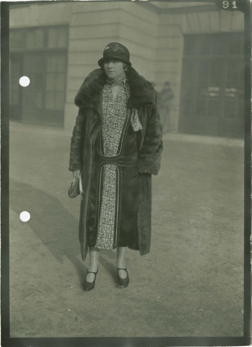 Frau in Kleid und Mantel auf dem Rennplatz