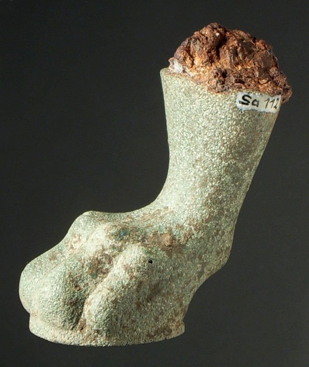 Löwenfuß, wohl von einem Dreifuß (Stabdreifuß), ungereinigt, unten offen, Kernmasse sichtbar, oben Reste der eisernen Stütze