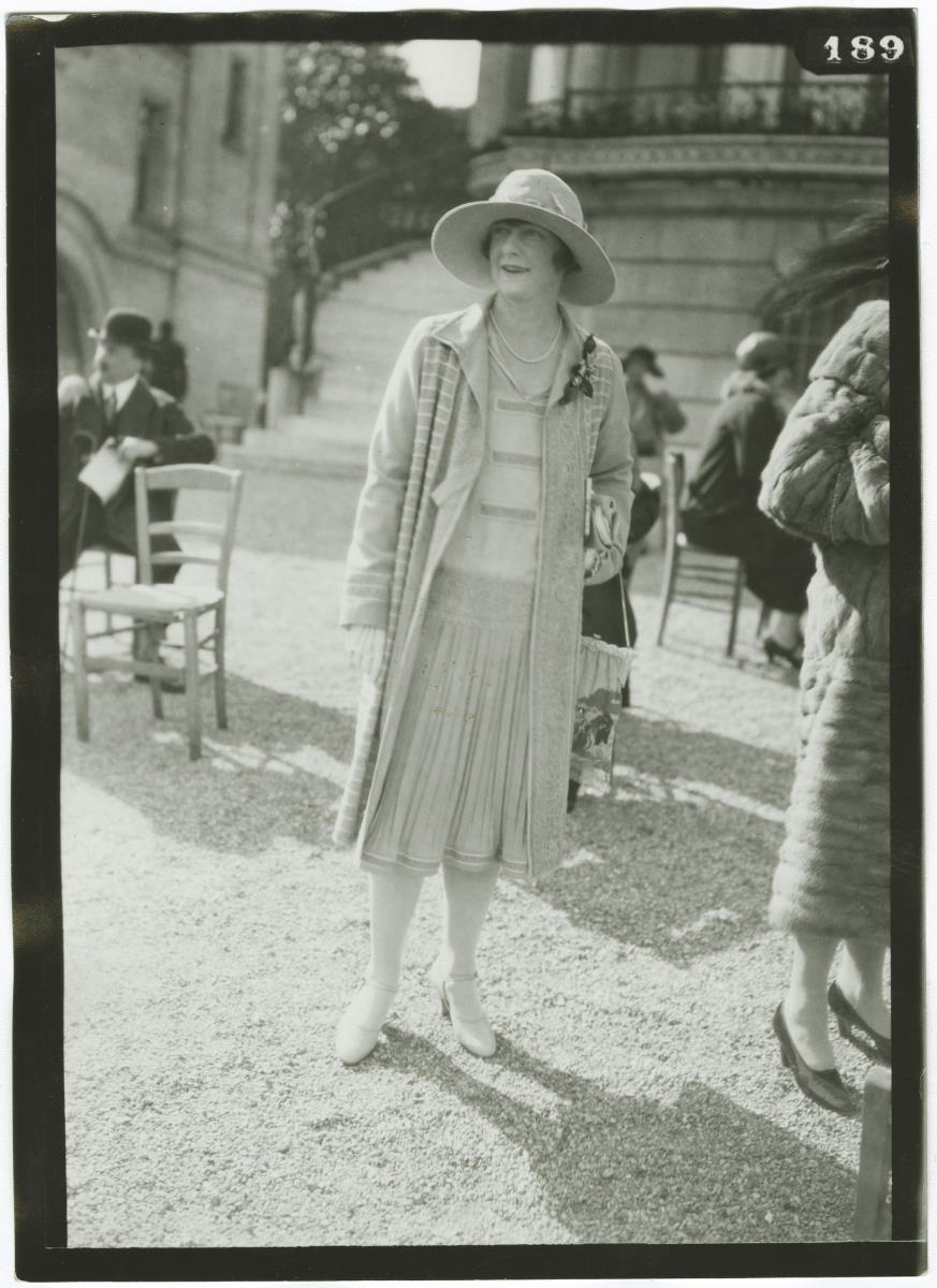 Frau in Kleid und Mantel auf dem Rennplatz in Longchamp