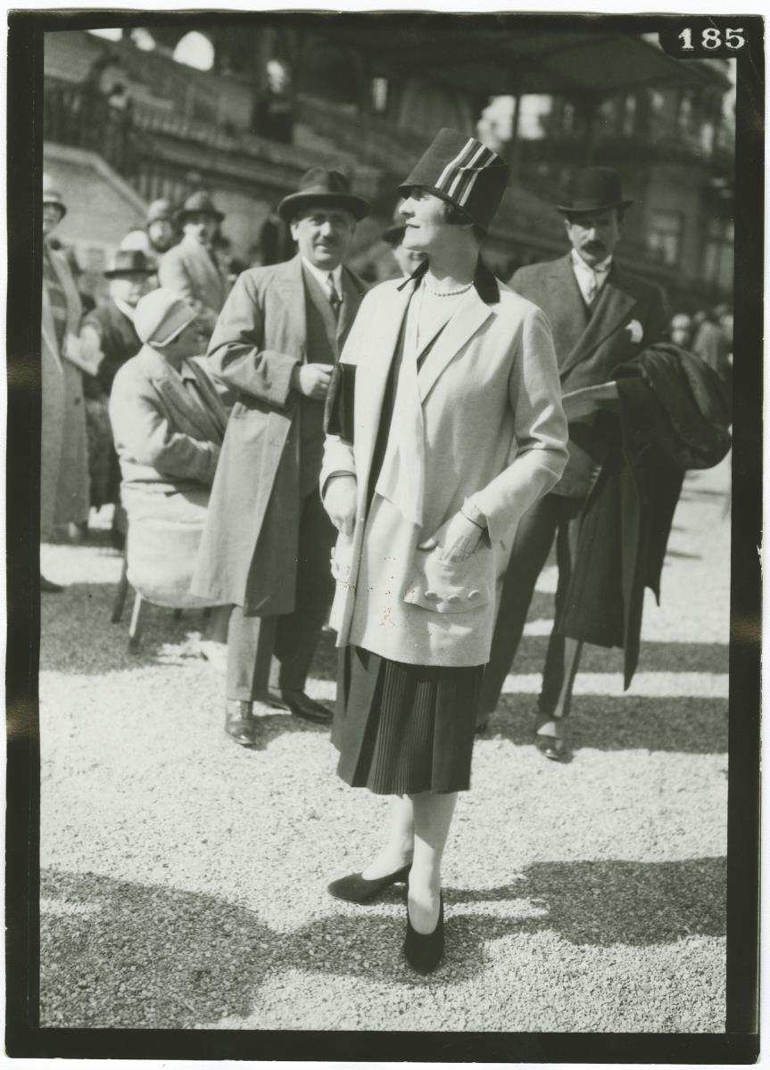Frau in Kleid und Mantel auf dem Rennplatz in Longchamp