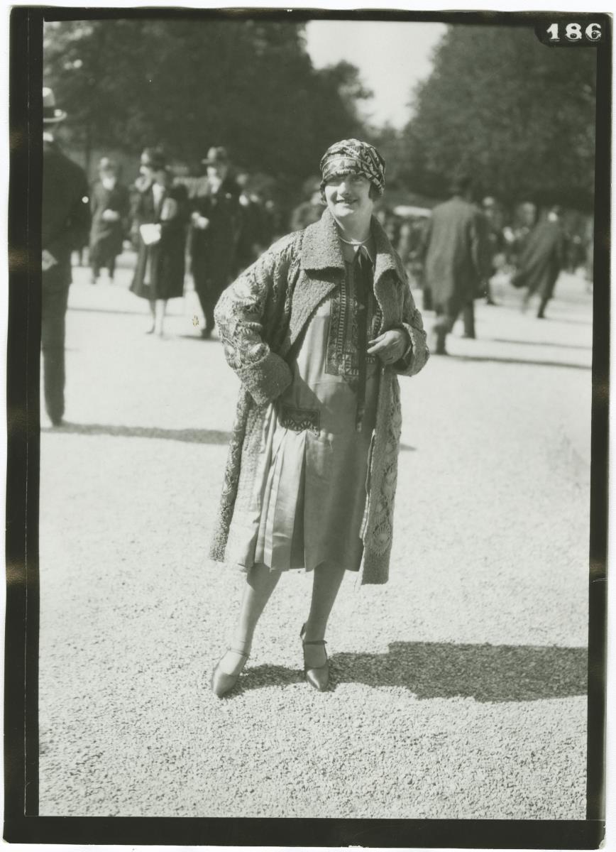 Frau in Kleid und Mantel auf dem Rennplatz in Longchamp