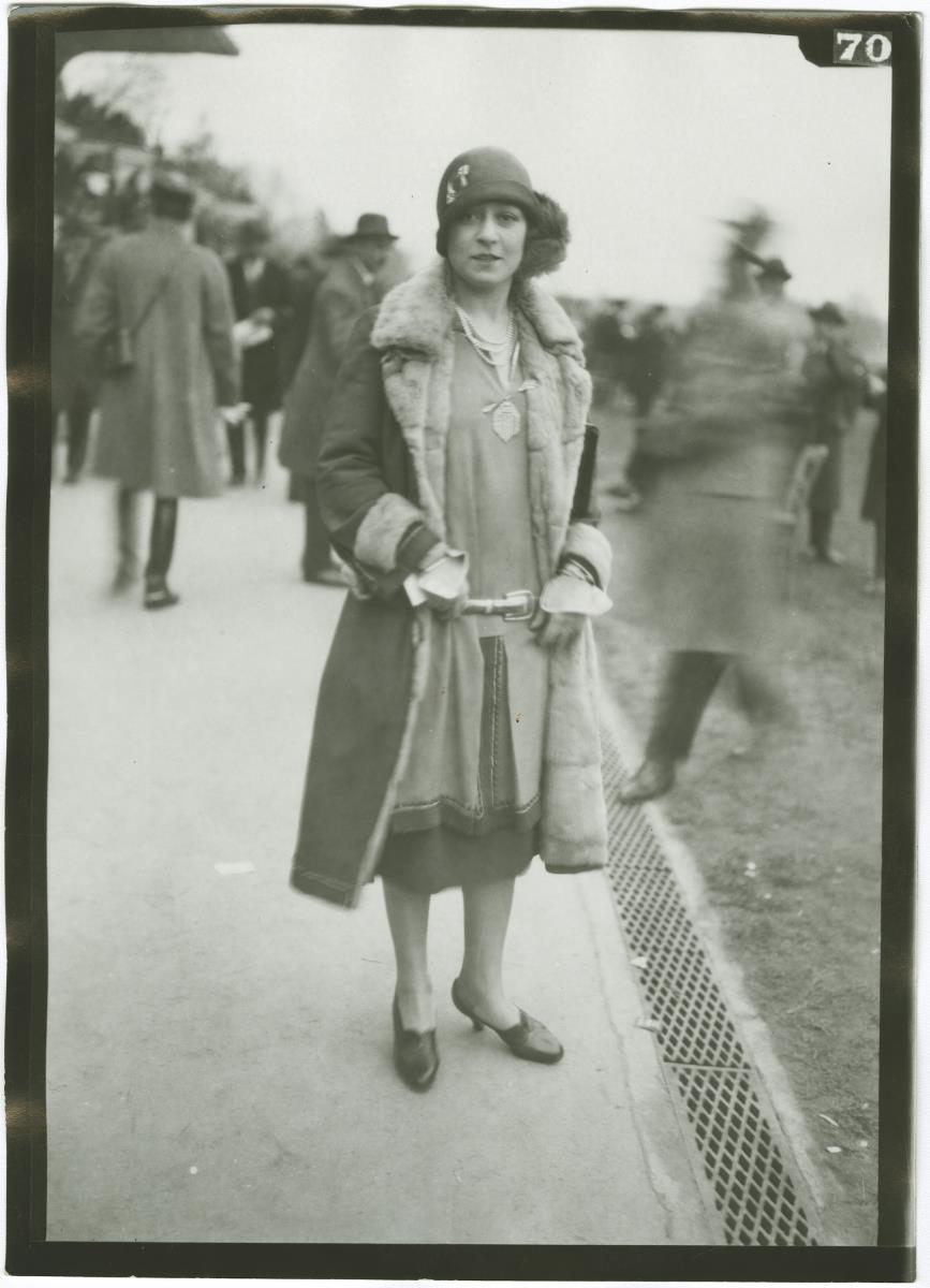 Frau in Kleid und Mantel auf dem Rennplatz in Auteuil