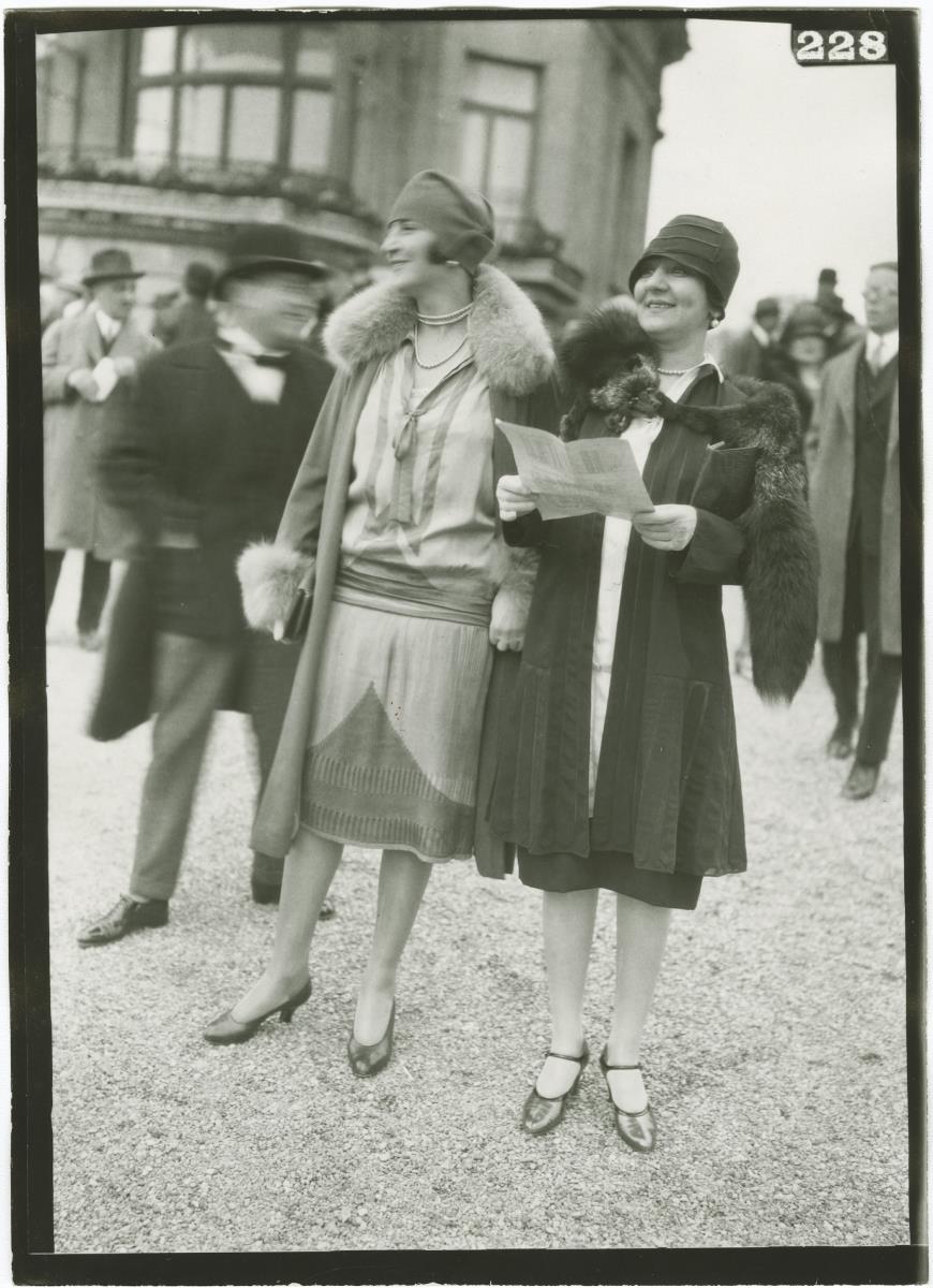 Frauen in Kleidern und Mänteln auf dem Rennplatz in Longchamp