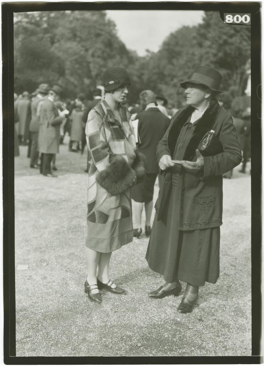 Frau in Mantel und Frau in Ensemble auf dem Rennplatz in Longchamp