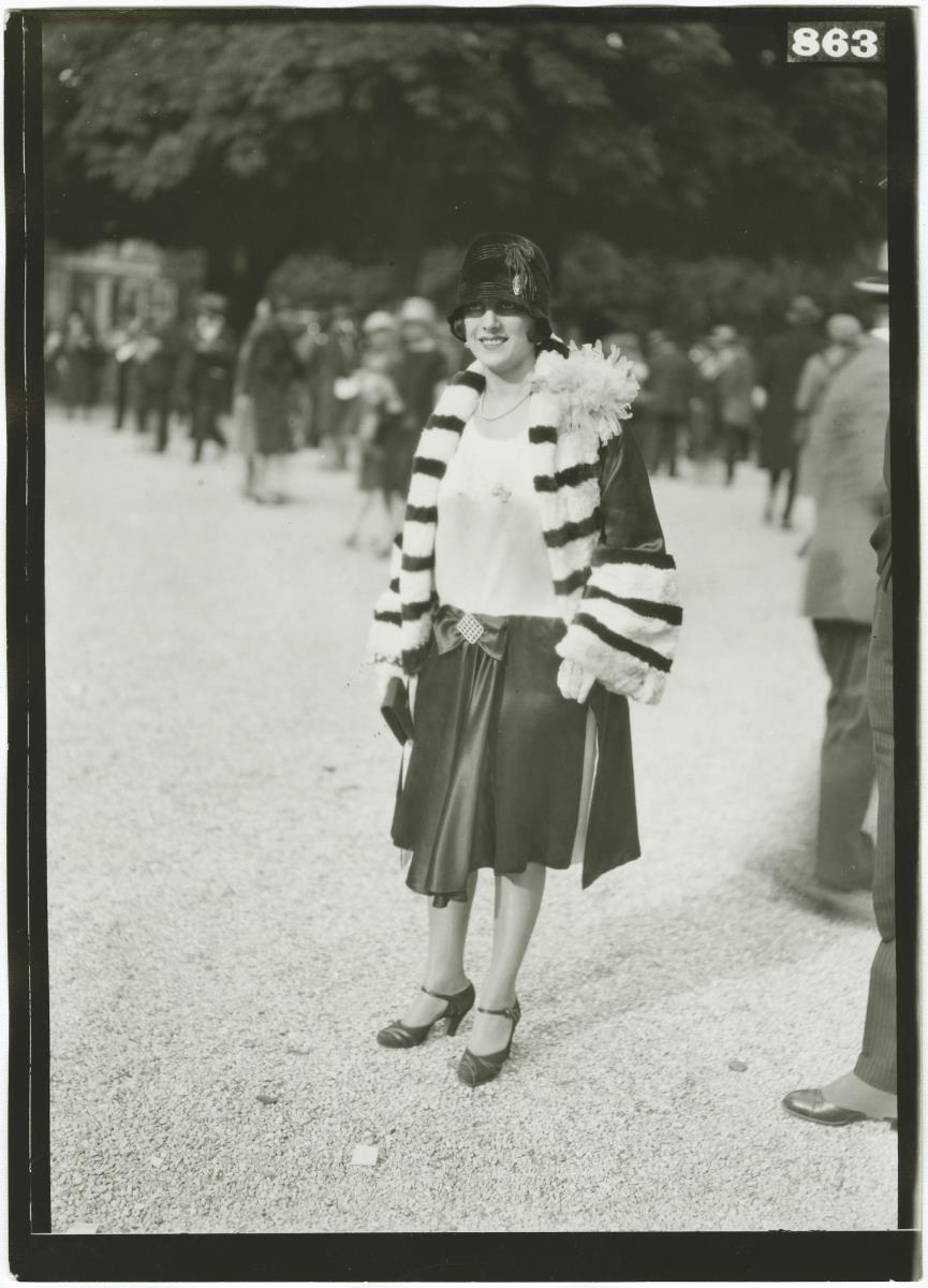 Frau in Kleid und Mantel auf dem Rennplatz in Longchamp