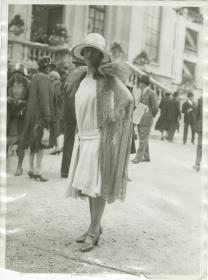 Frau in Kleid und Mantel auf dem Rennplatz