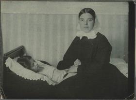 Kind im Bett und Frau mit Kopftuch