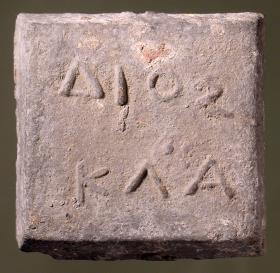 Einstufiges quadratisches Gewicht (attisch-äginetischer Standard, Halbminenstück) mit griechischer Inschrift (ΔΙΟΣ / ΚΛΑ)