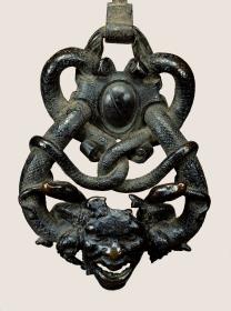 Schlangen um Maske und Wappen