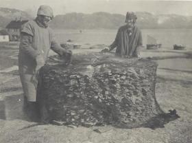 Zwei Frauen an einem Stapel getrockneter Fische