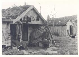 Samin vor einem Holzhaus