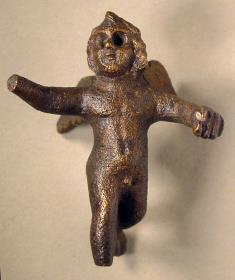 Kleine römische Amor- / Erosstatuette, laufend, beide Arme vorgestreckt, die rechte Hand und der rechte Fuß sind weggebrochen; in der Linken hält er etwas