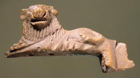 Statuette eines gelagerten Löwen, Kopf en face drehend, Beschlag eines Geräts oder Gefäßes; sehr dunkle Patina