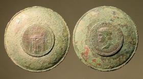 Römischer Dosenspiegel mit eingelassener, entzweigesägter Münze. A: Kopf des Nero mit Umschrift / B: Triumphbogen S. C.