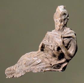 Statuette eines sitzenden Pan; mit beiden Händen hält er die Syrinx; um die Schultern hat er ein Fell oder ein Gewand geknüpft