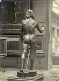 Johannes der Täufer im Musée du Luxembourg, hinter der Figur eine Plattenkamera