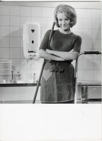 Junkers, Hausfrau mit Putzmitteln an Küchenspüle mit Gas-Durchlauferhitzer (Werbung für Junkers Quell)