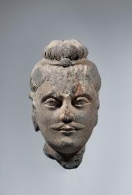 Kopf eines Buddha mit Schnurrbart und Schmuckband um Ushnisha