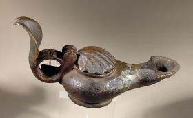 Hellenistische Lampe mit aufgebogenem Blatt am Griff und  muschelförmigem Deckel