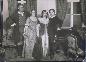 Frauen in Kleidern und Männer in Anzügen. Schauspieler in historisierenden Theaterkostümen