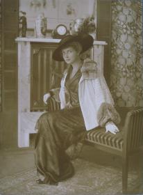 Frau in Kleid und Jacke mit Hut