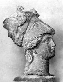 Athenakopf mit korinthischem Helm, daran zwei Greifen im Relief; Helmbusch abgebrochen; Helmspitze vorne eingedrückt