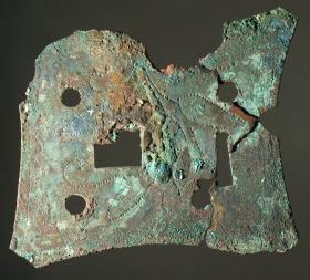 Schlossblech der Holztruhe, in der die Gegenstände geborgen waren. Verzierung in Punkten eingestochen. In drei Teile zerbrochen und defekt